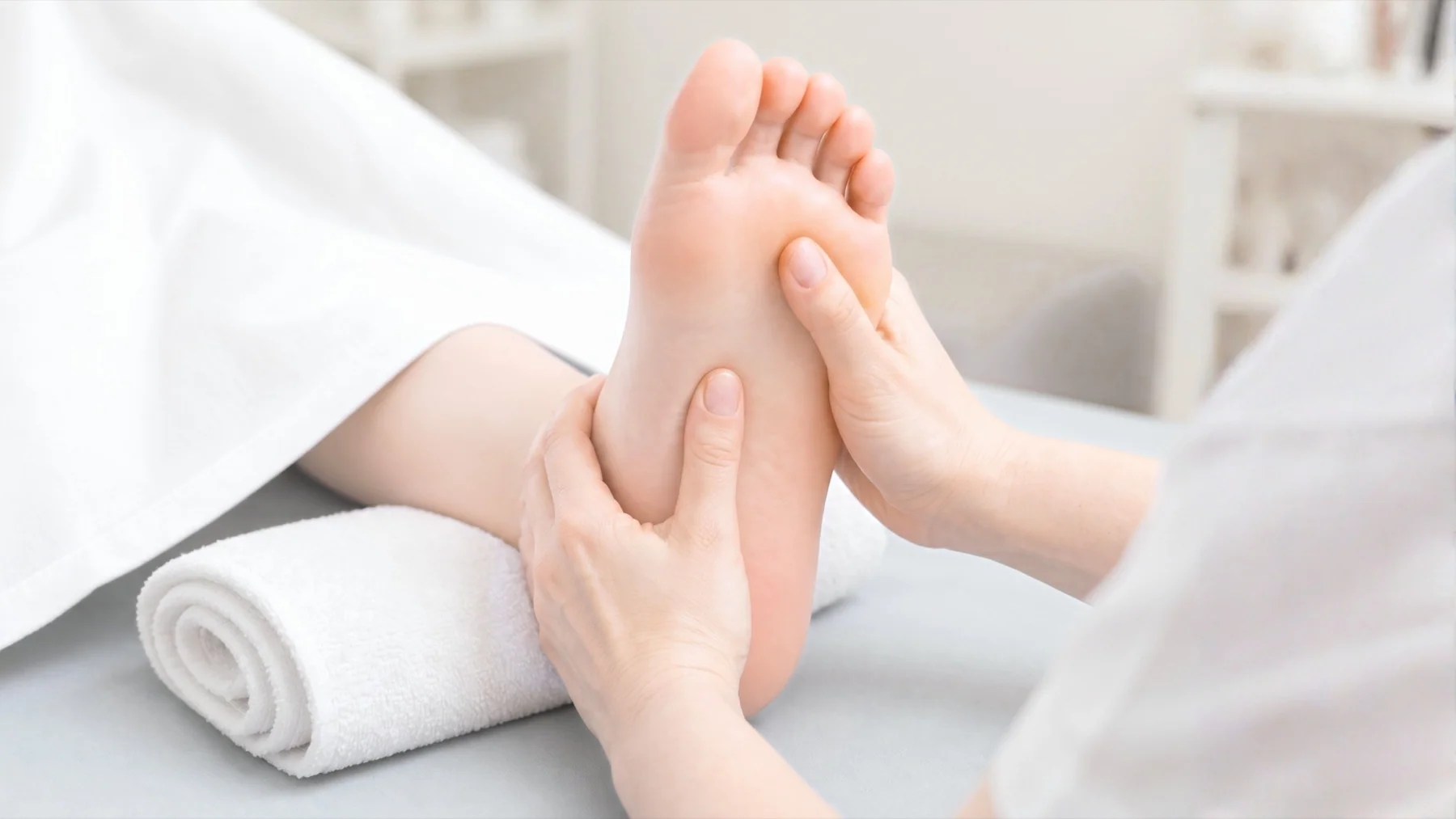 A professional Bednbody massage therapist performing foot reflex massage on a relaxed client at home